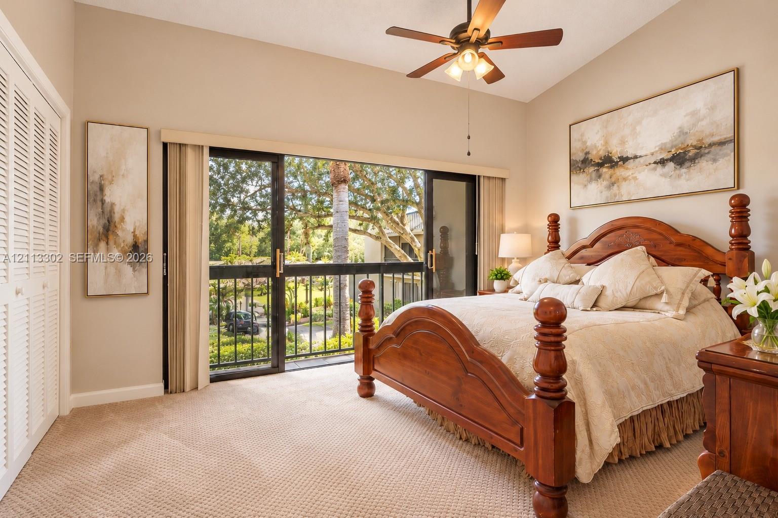 Vaulted ceilings featuring a central paddle fan, wall-to-wall carpeting, floor-to-ceiling sliding glass doors with metal frame, and bi-fold closet doors