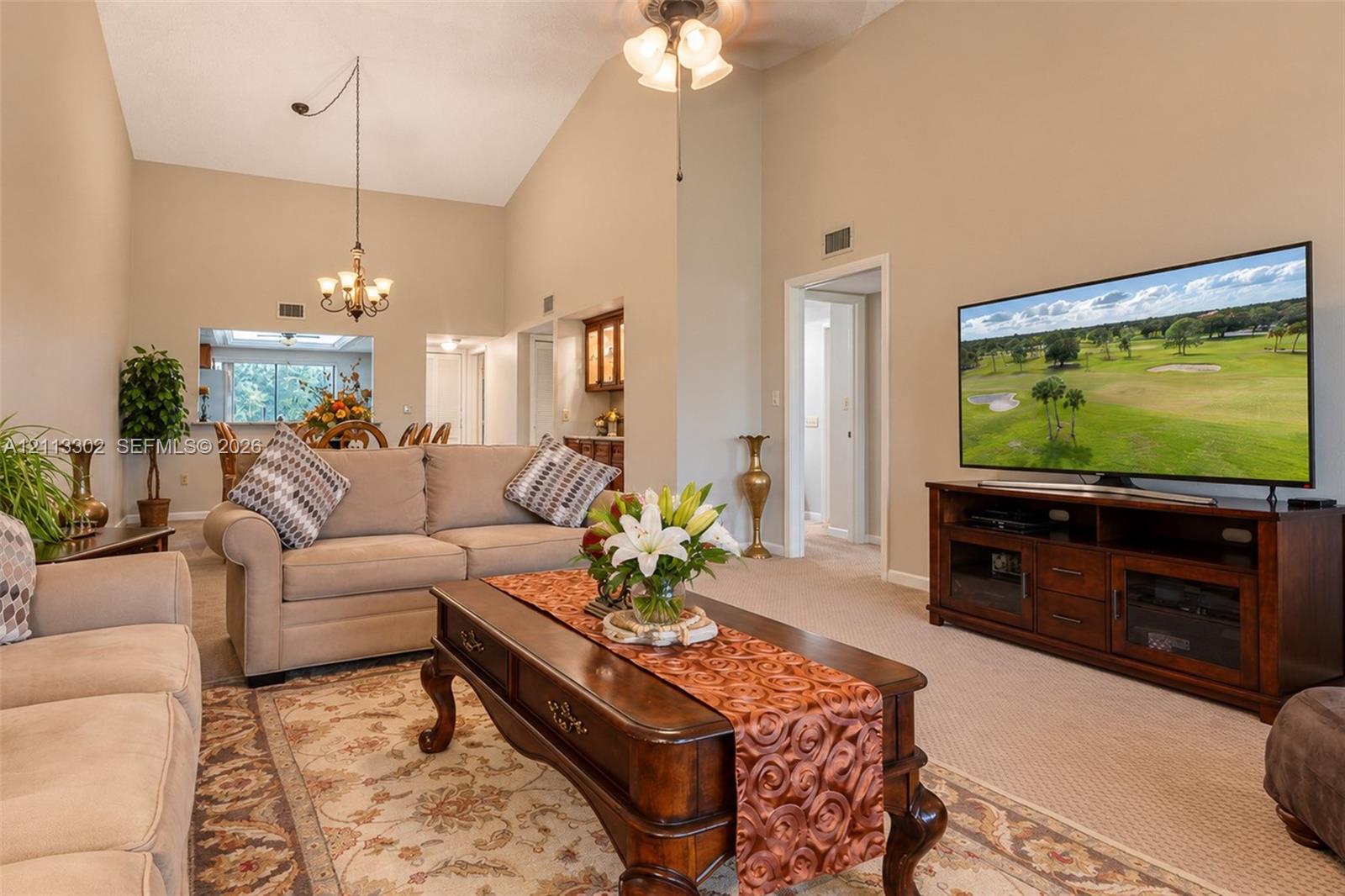 Vaulted ceilings, formal chandelier, and built-in cabinetry featuring glass-front display shelving