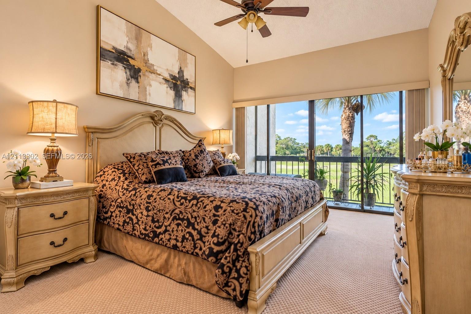 Vaulted ceiling, ceiling fan, and floor-to-ceiling sliding glass doors opening to a balcony with exterior greenery