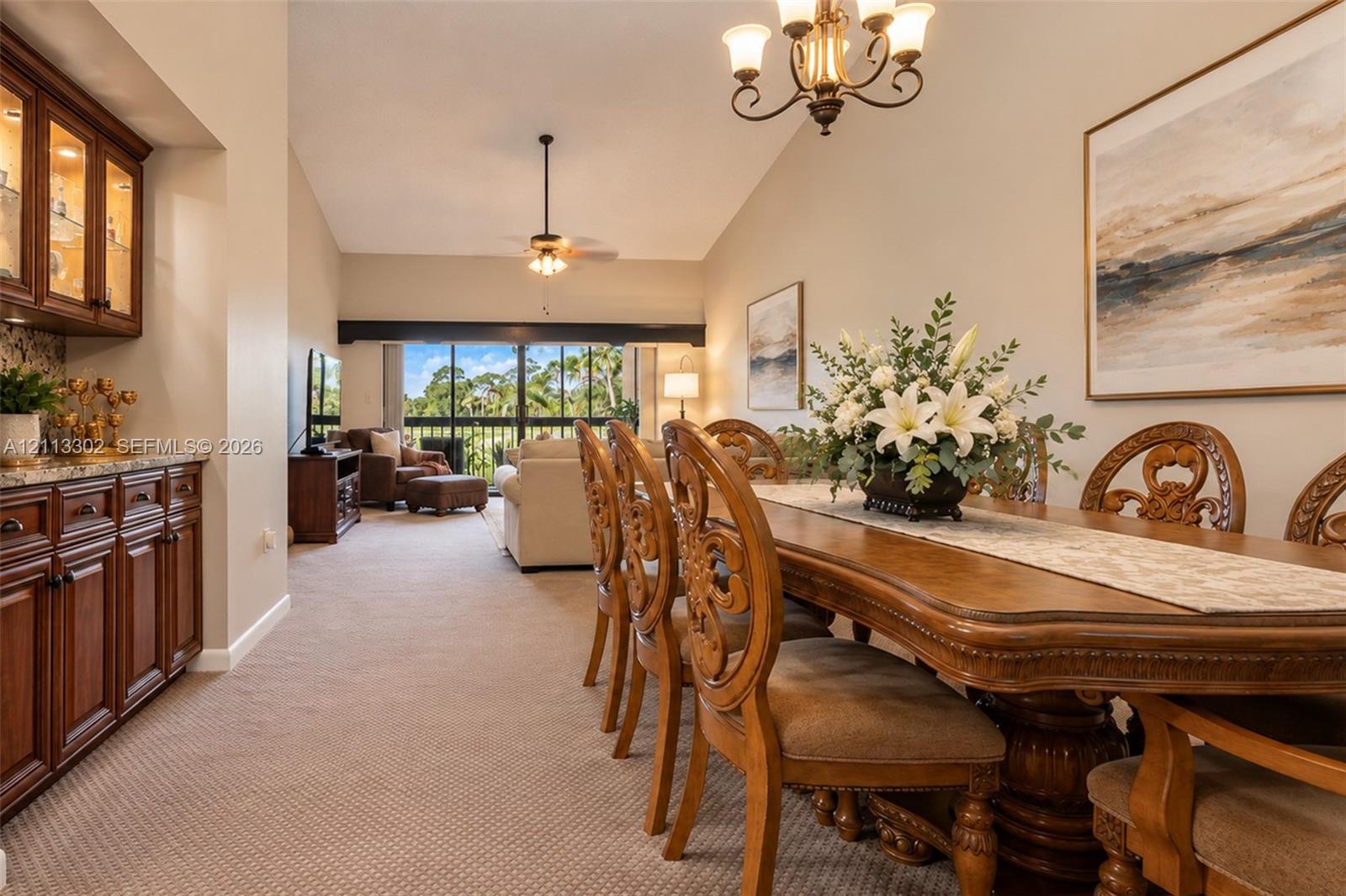 Dining area featuring vaulted ceilings, built-in wooden cabinetry with countertop space, a decorative chandelier, and a floor-to-ceiling sliding glass door