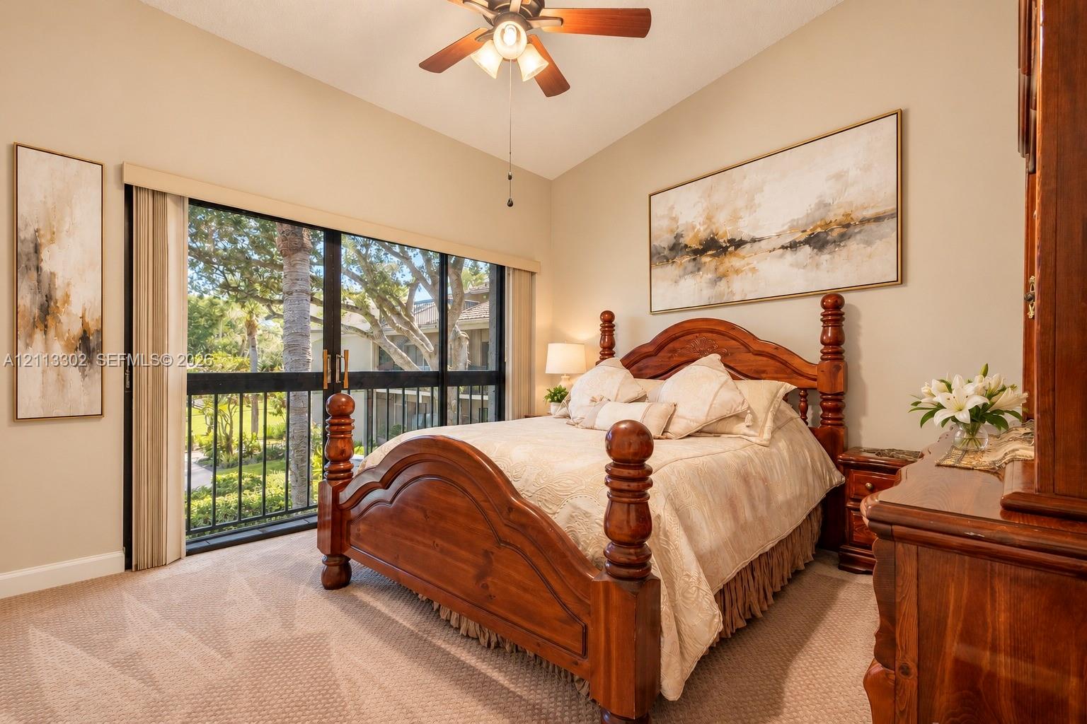 Vaulted ceiling featuring a central ceiling fan with integrated lighting, wall-to-wall carpeting, and sliding glass doors with black framing