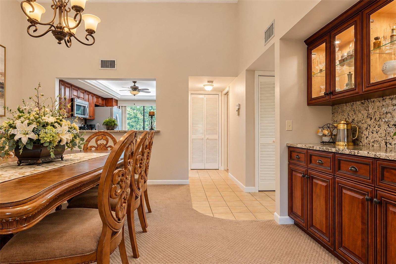 Dining area featuring high vaulted ceilings, wrought-iron chandelier, and built-in cabinetry with glass-front uppers and stone countertops