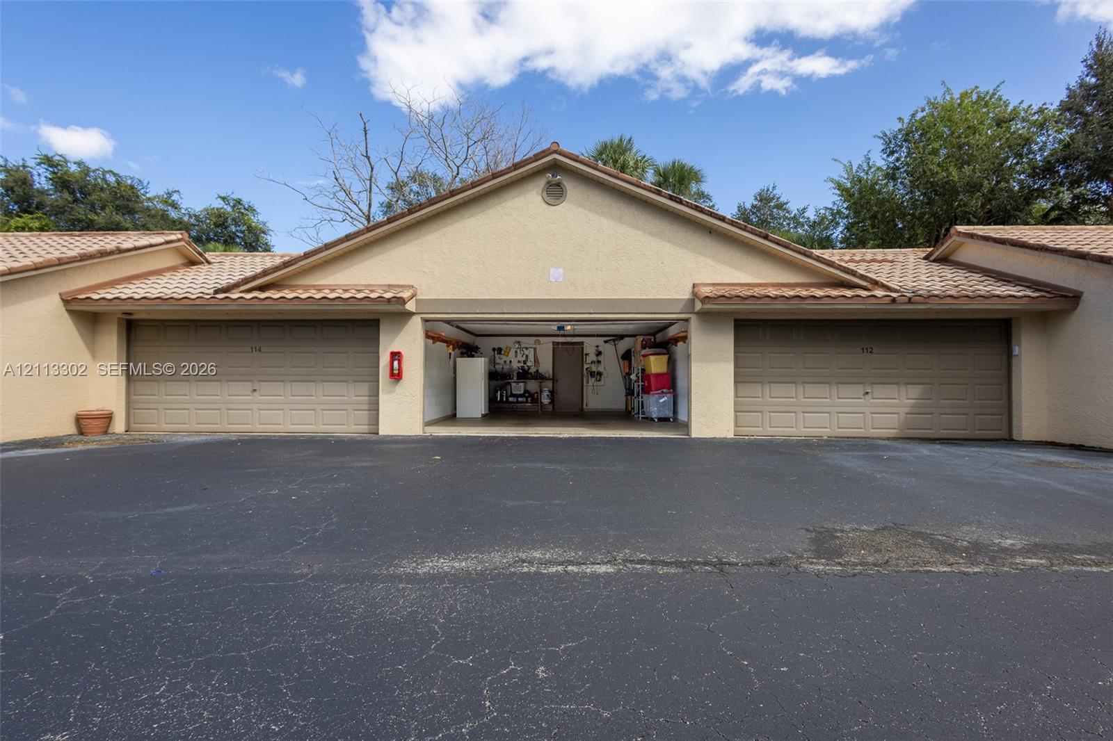 Multi-bay garage exterior featuring stucco siding, tile roofing, and paved driveway space