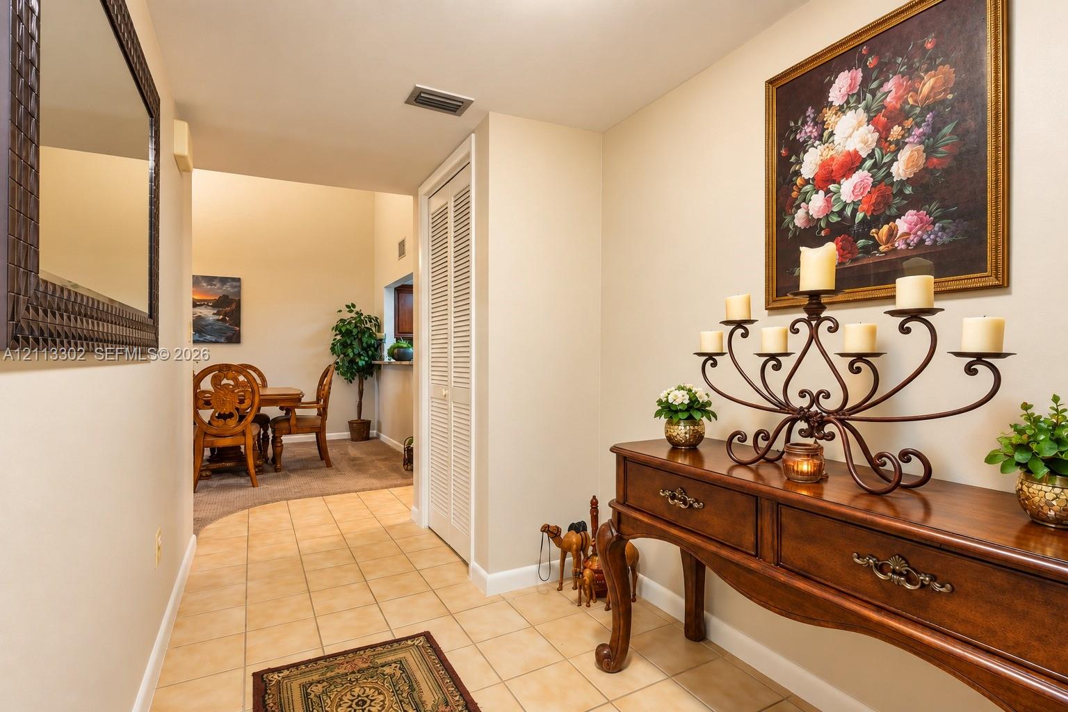 Entryway featuring ceramic tile flooring, neutral wall color, and a full-height closet with louvered doors