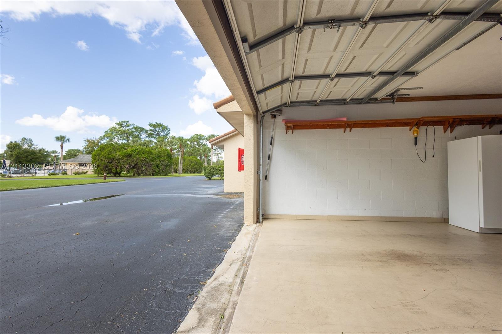 Garage interior featuring painted concrete block walls, a concrete floor, overhead door tracks, and built-in wood shelving