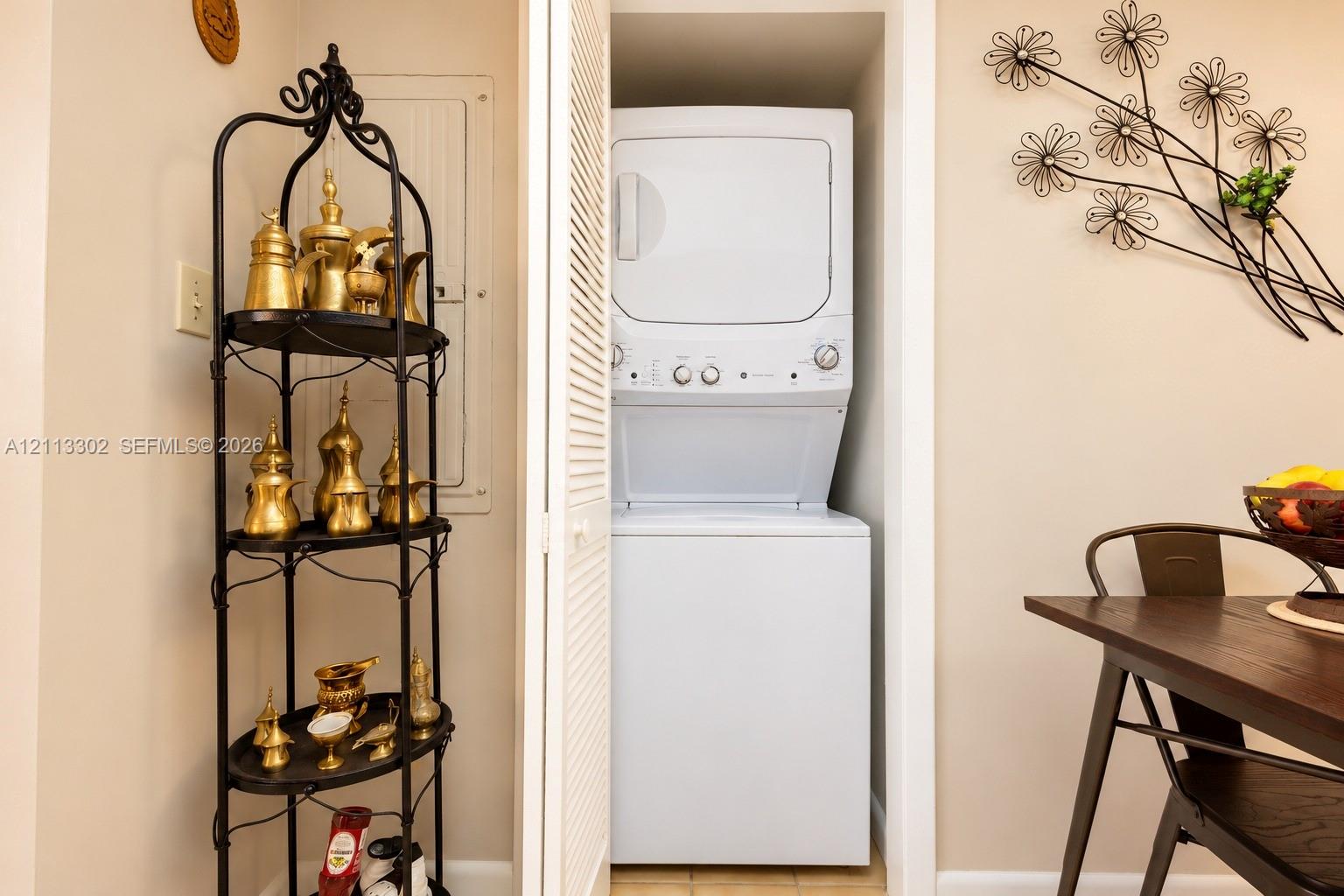Laundry area featuring a stacked washer and dryer unit concealed by louvered bi-fold doors