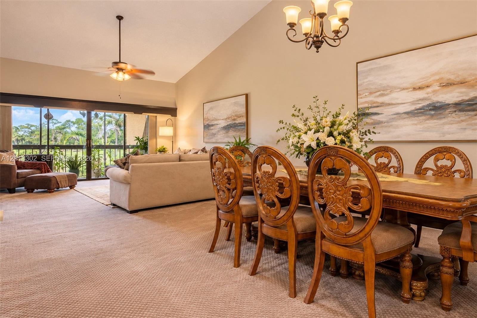 Vaulted ceilings, expansive glass sliding doors, integrated ceiling fan, and traditional multi-arm chandelier