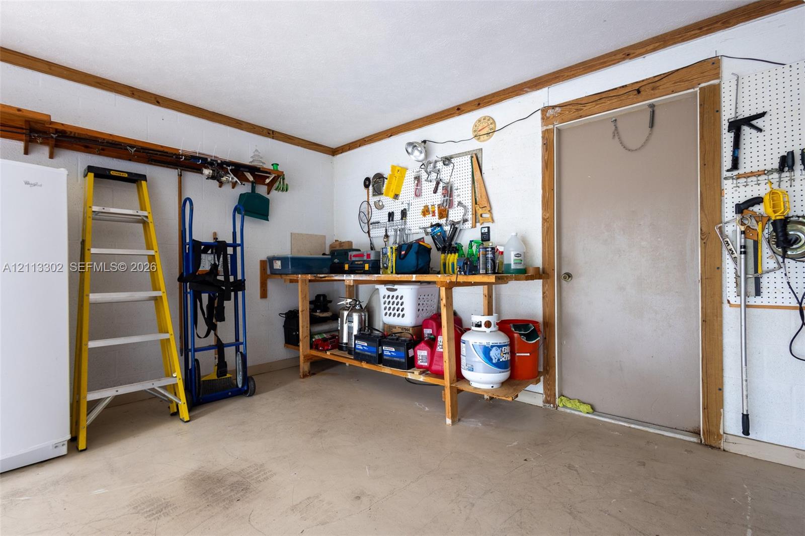 Garage space featuring a built-in wooden workbench, wall-mounted pegboard organization, and wooden ceiling trim