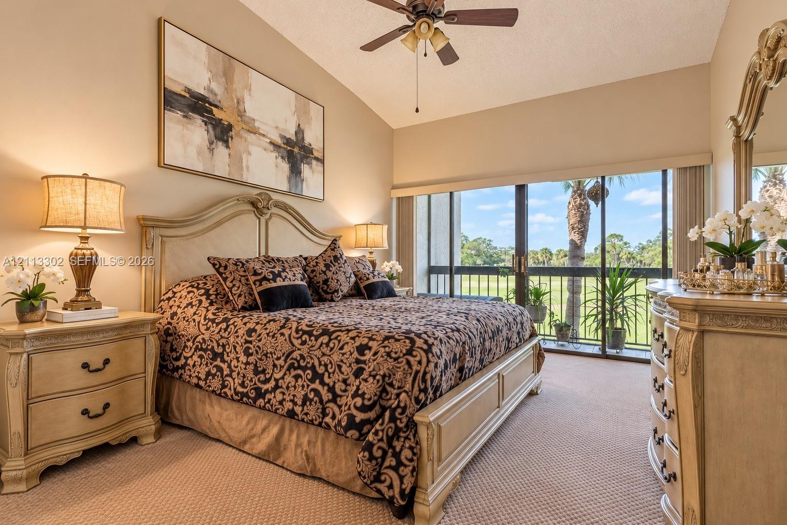 Vaulted ceiling featuring a central lighted ceiling fan, wall-to-wall carpeting, and sliding glass doors with exterior balcony access