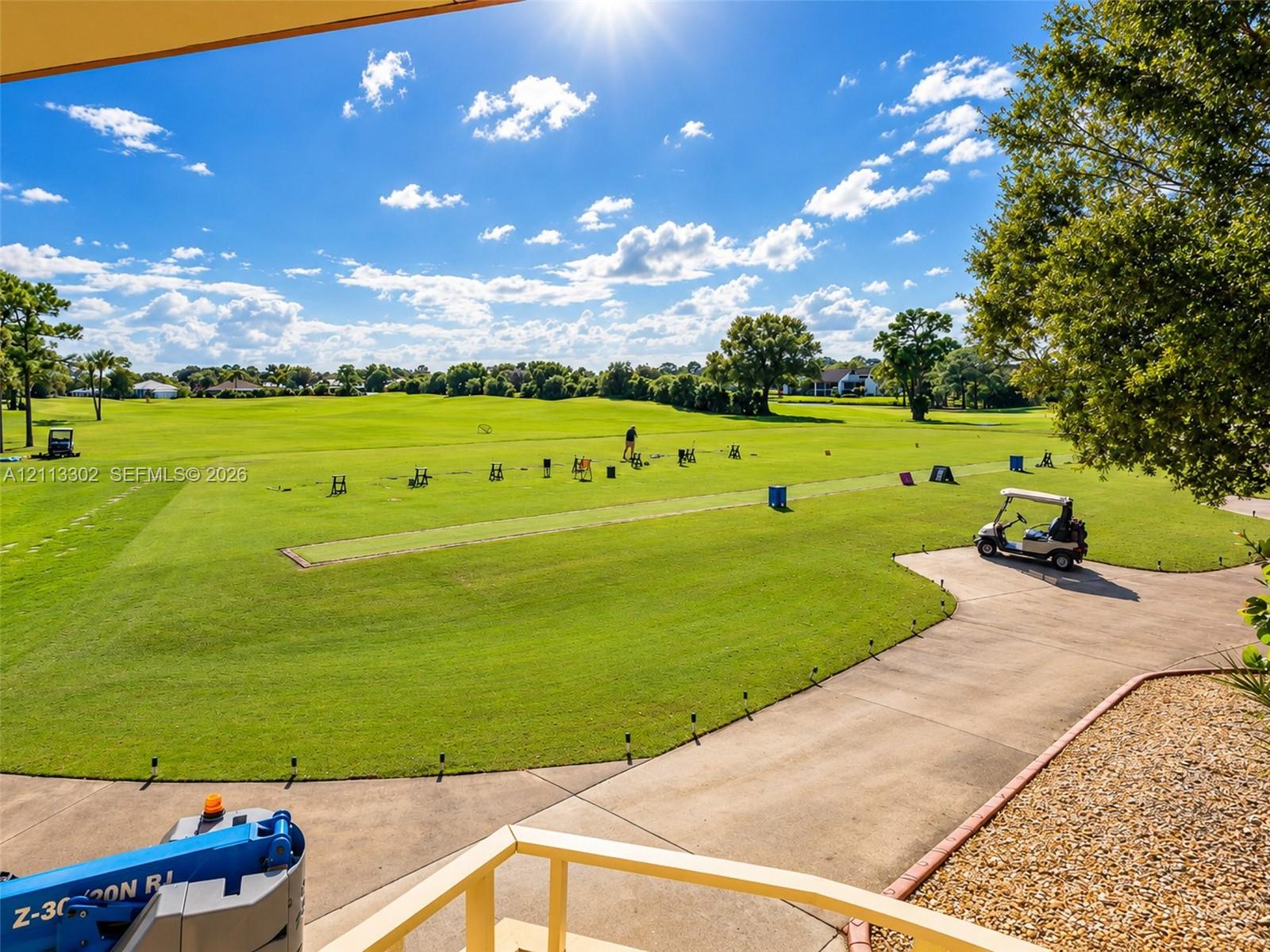 Expansive golf course grounds featuring manicured turf, mature trees, and a paved cart path