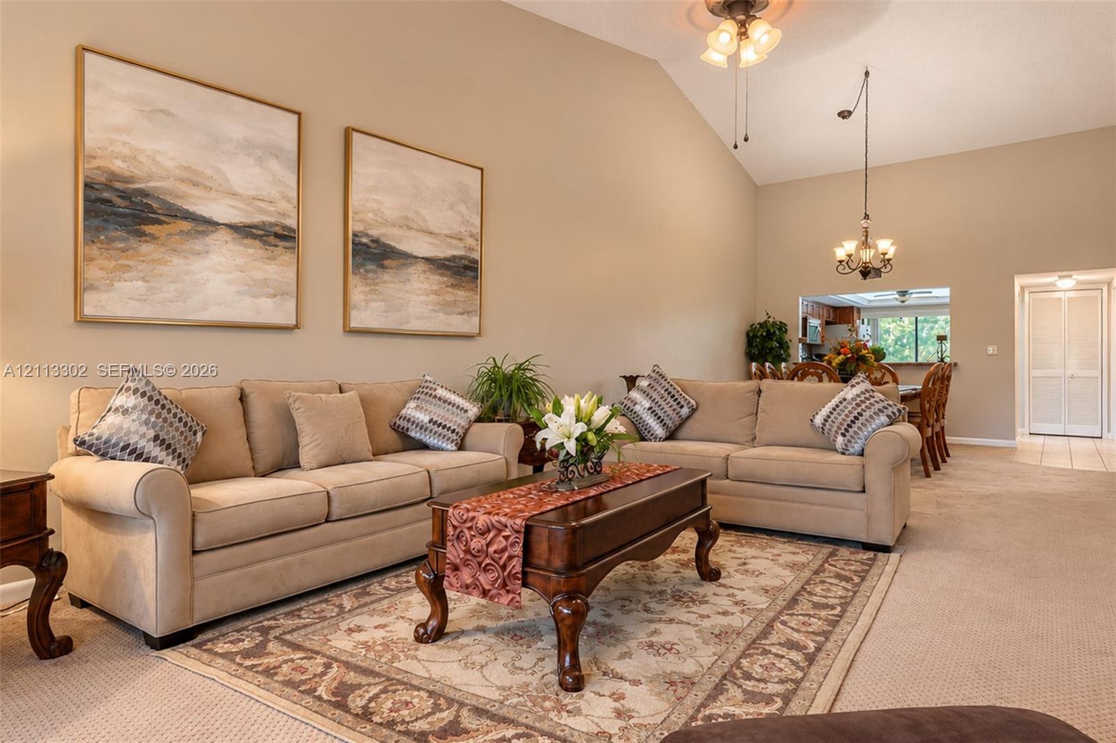 Vaulted ceilings, neutral wall tones, multi-arm chandelier lighting, and built-in closet doors