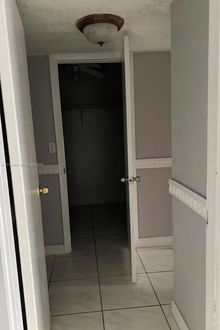 Large-format tile flooring, walls featuring decorative chair rail molding, and a built-in closet with overhead lighting