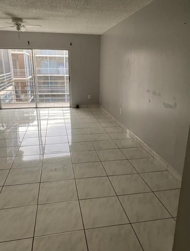 Ceramic tile flooring, neutral wall finishes, sliding glass door, and a ceiling fan