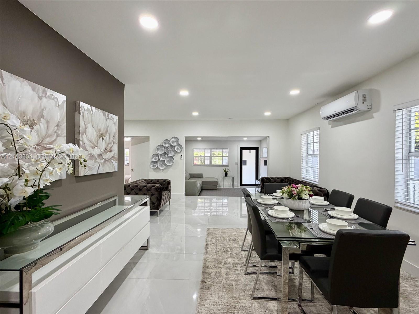 Open-concept space featuring polished tile flooring, recessed lighting, wall-mounted climate control unit, and crisp neutral wall tones Open-concept space featuring polished tile flooring, recessed lighting, wall-mounted climate control unit, and crisp neutral wall tones