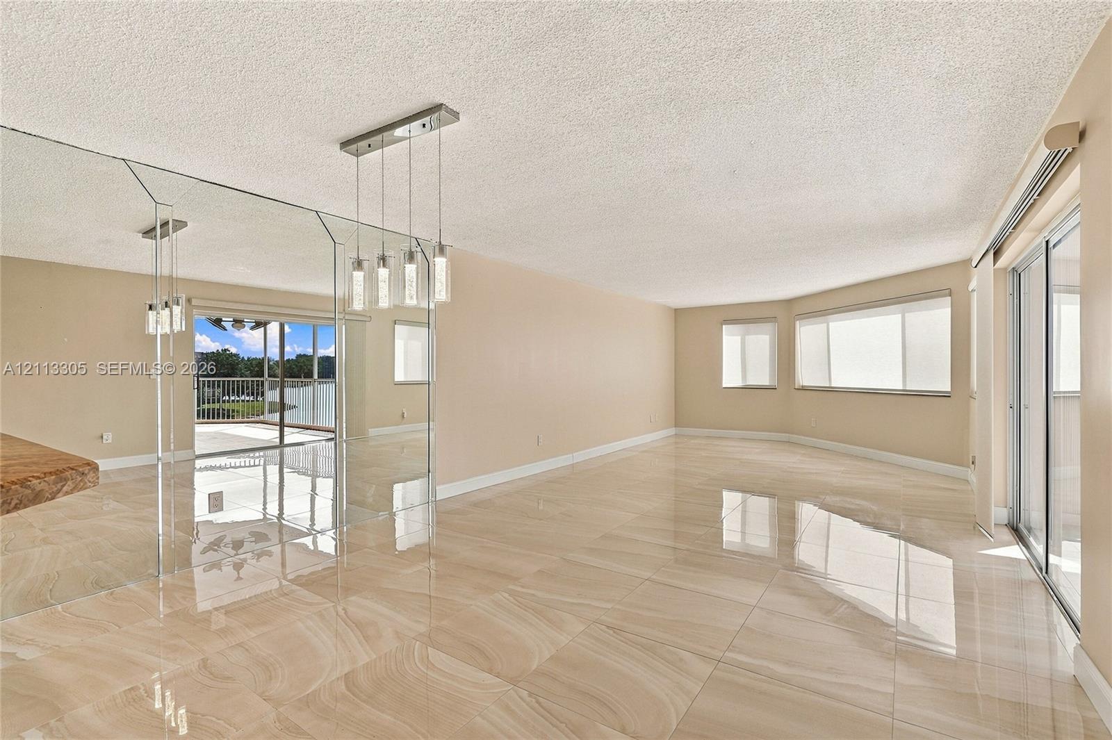 Large-format polished tile flooring, wall-to-wall mirrored accent paneling, multi-pendant linear lighting fixture, and sliding glass doors with window treatments
