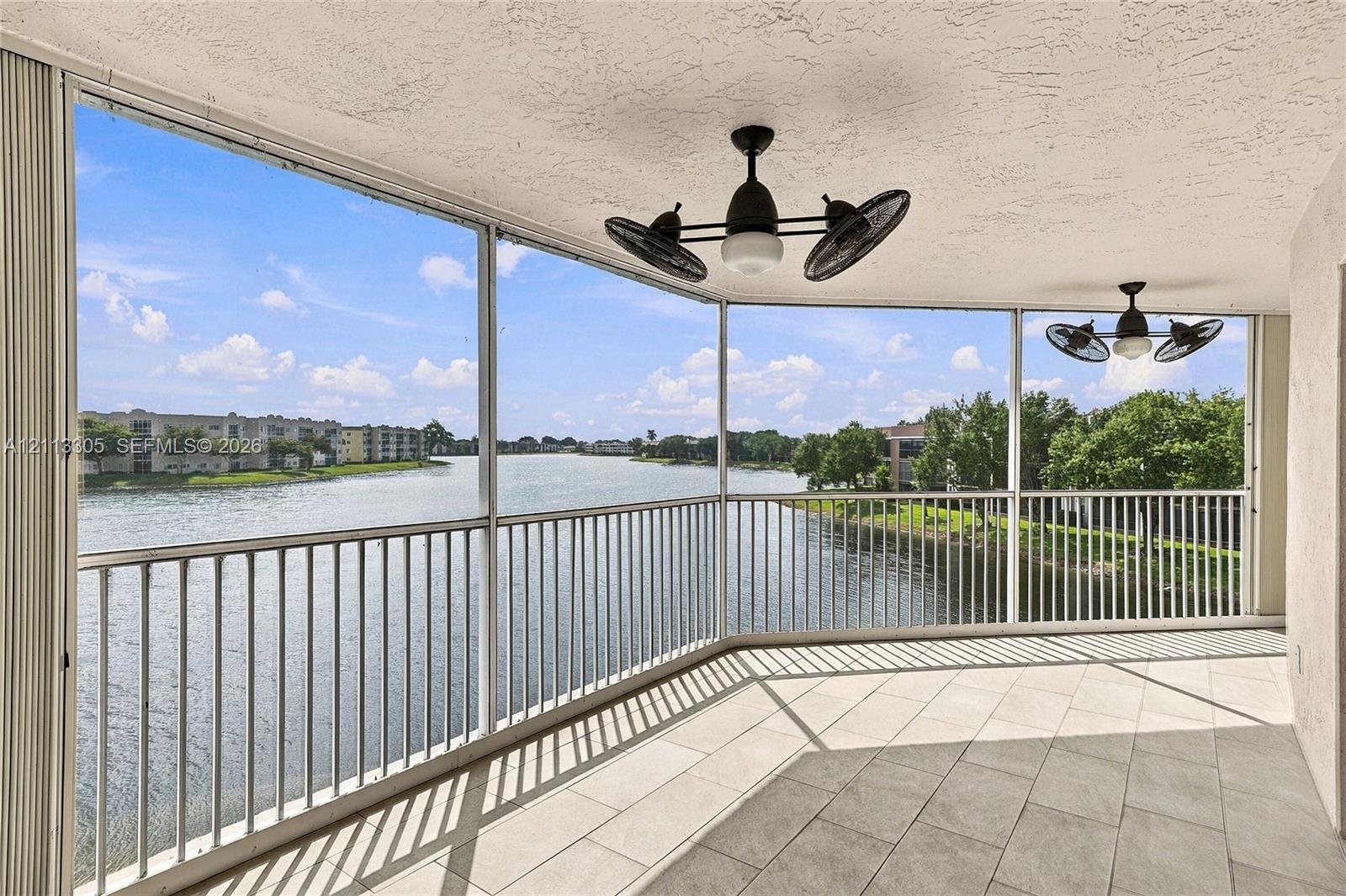 Screened-in balcony featuring tile flooring, metal railings, and dual multi-blade ceiling fans with integrated lighting
