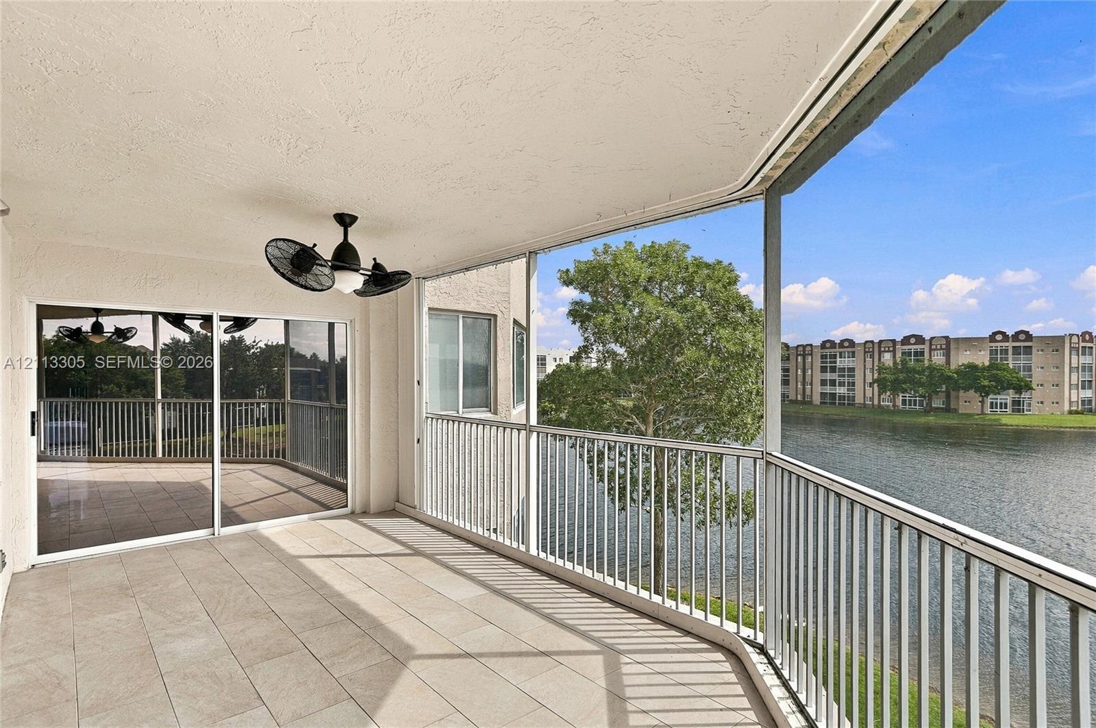 Screened-in balcony featuring tile flooring, metal railings, and a ceiling-mounted fan