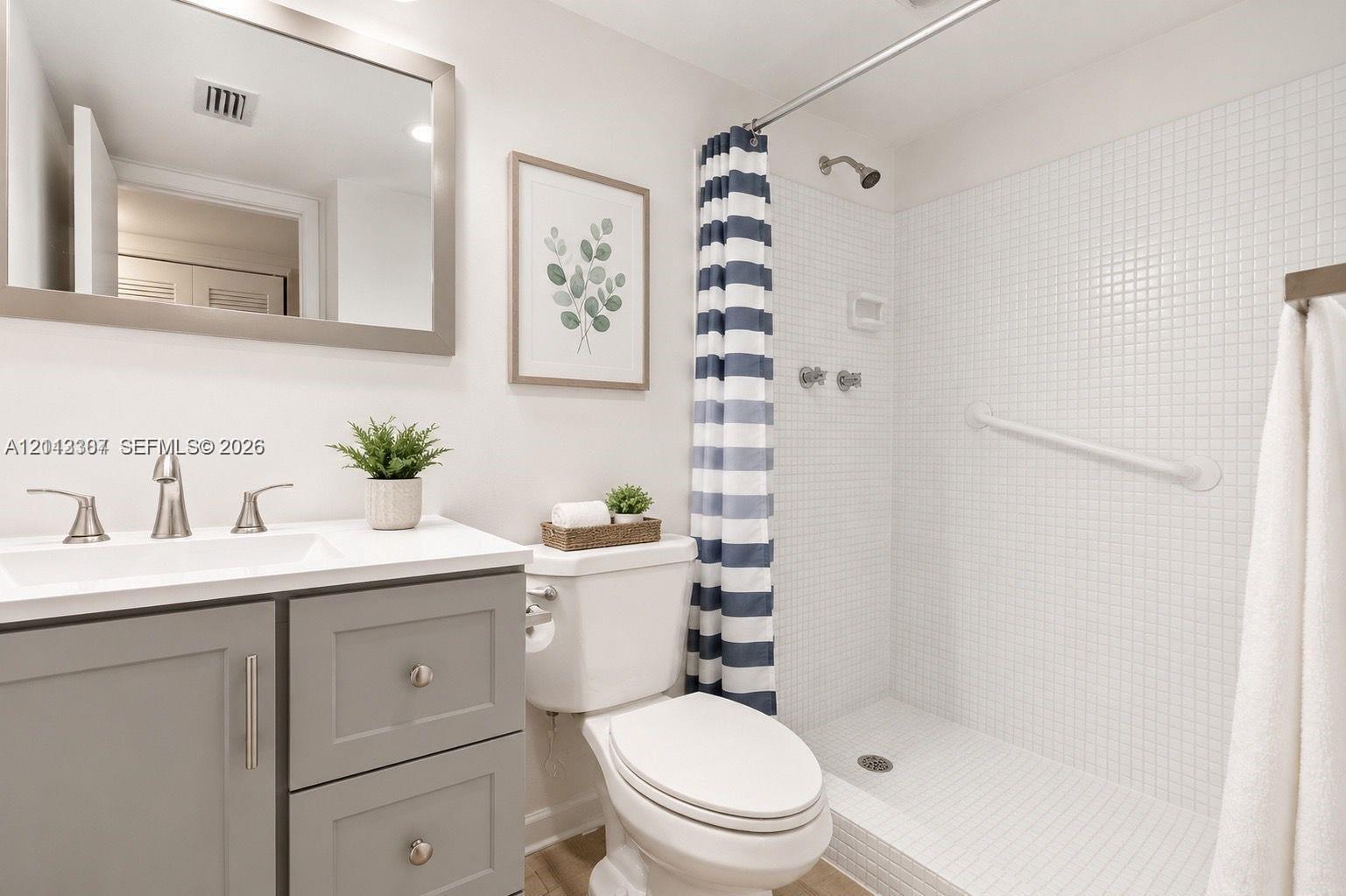 Bathroom featuring a vanity with grey cabinetry, white countertop, rectangular sink, and polished metal faucet Bathroom featuring a vanity with grey cabinetry, white countertop, rectangular sink, and polished metal faucet