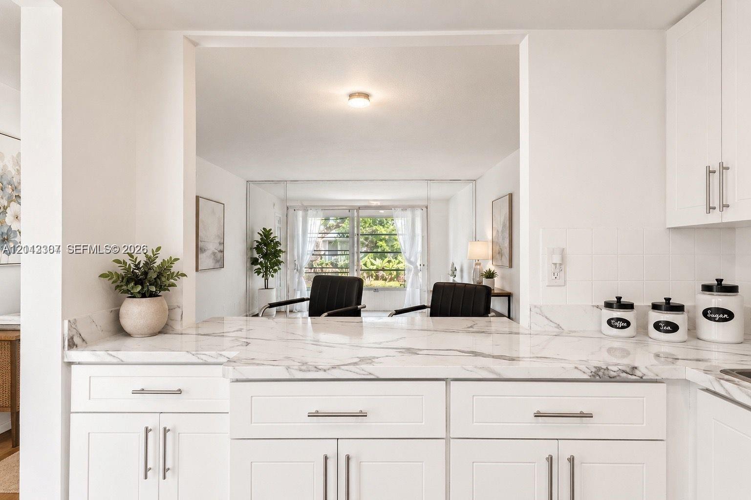 Kitchen featuring white shaker-style cabinetry, stone-patterned countertops, and tile backsplash Kitchen featuring white shaker-style cabinetry, stone-patterned countertops, and tile backsplash