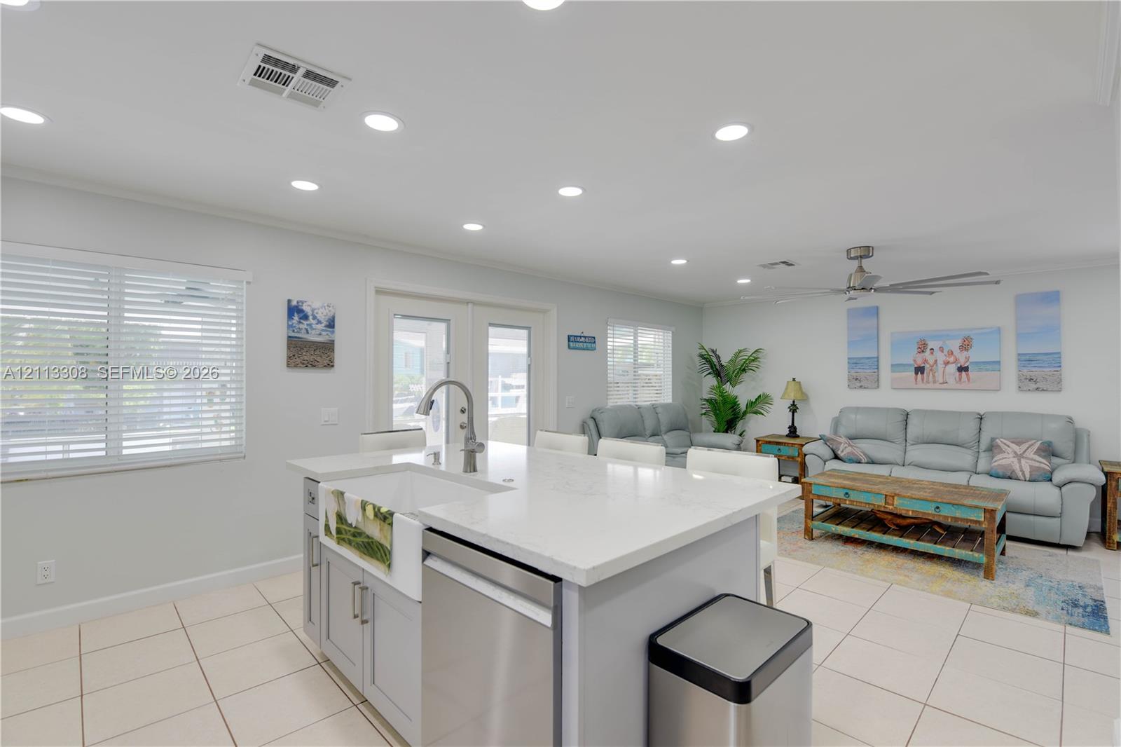Kitchen island featuring a farmhouse-style sink, quartz countertops, stainless steel dishwasher, recessed ceiling lighting, and tile flooring
