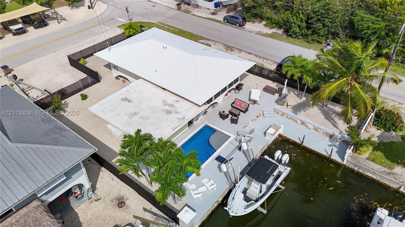 Waterfront property featuring an in-ground swimming pool, concrete bulkhead, boat lift, and concrete patio area