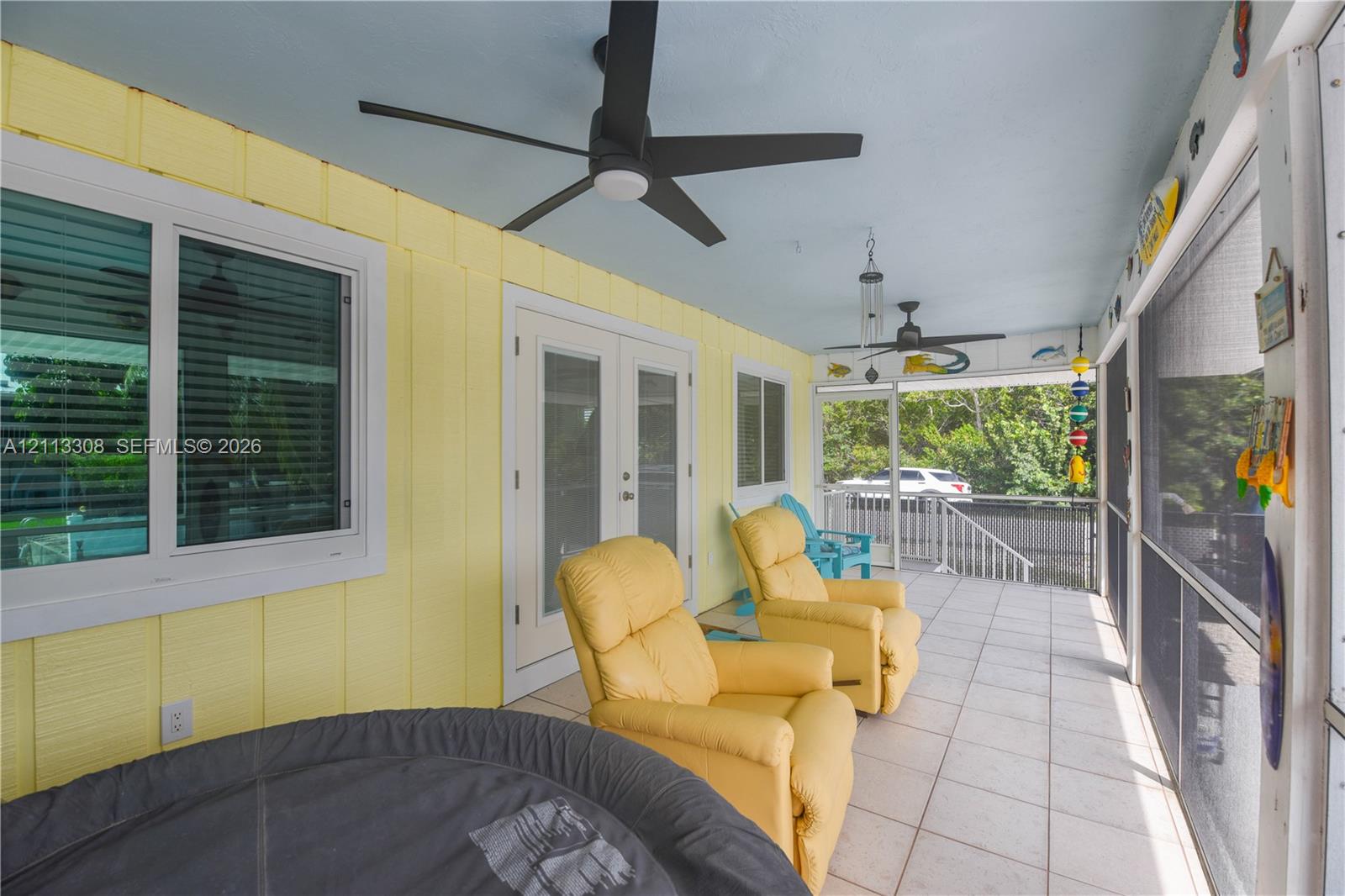 Screened-in porch featuring tile flooring, ceiling fans, vertical siding, and glass-paneled double doors