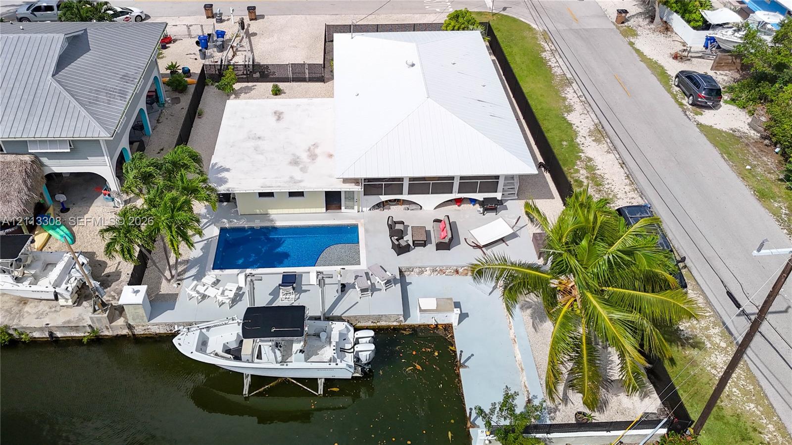Waterfront property featuring a private swimming pool, concrete bulkhead, boat lift, and screened-in patio area