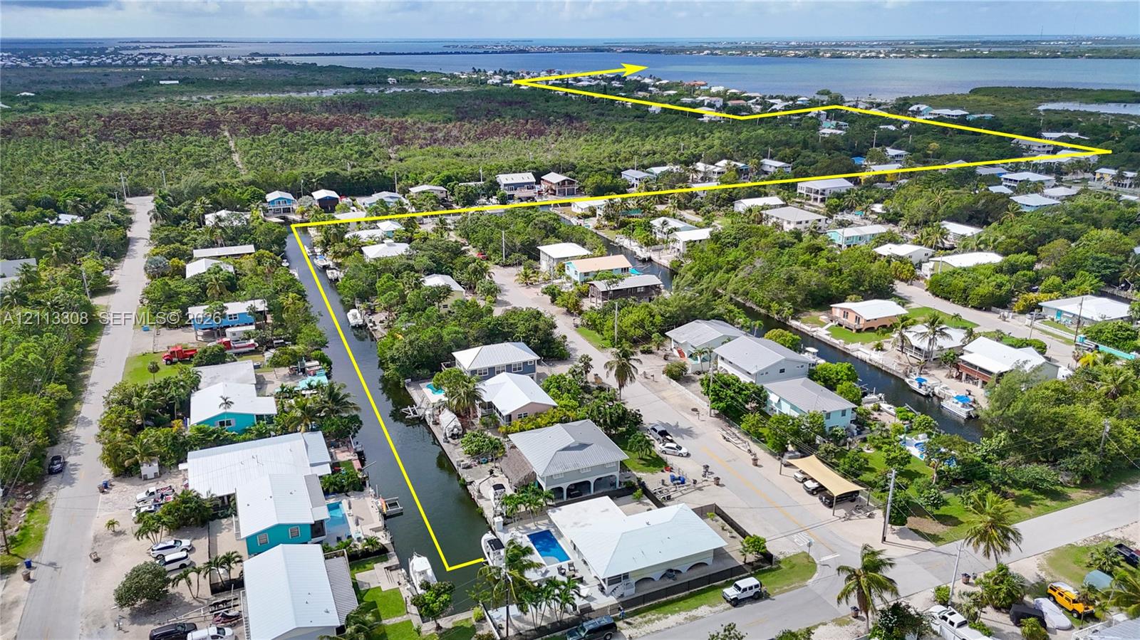 Aerial perspective of waterfront property featuring canal access, mature native vegetation, and coastal surroundings