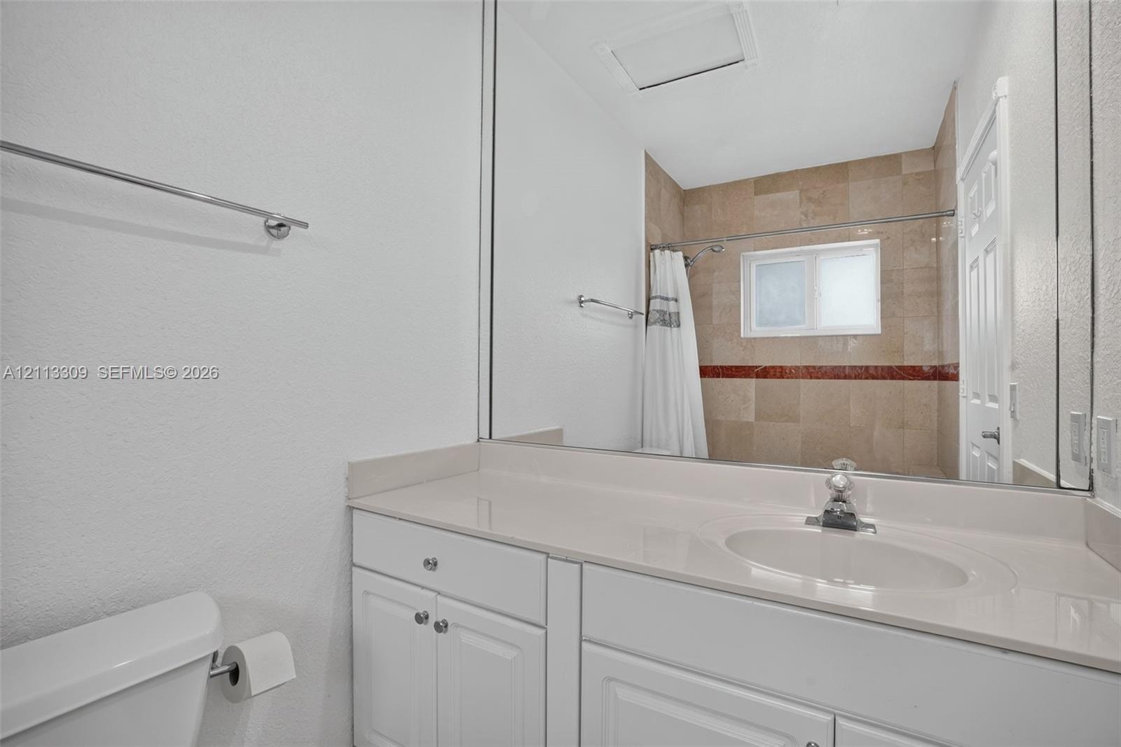 Bathroom featuring a white vanity with a solid surface countertop, an integrated sink, a full-width vanity mirror, and a tub-shower combination with tile surround