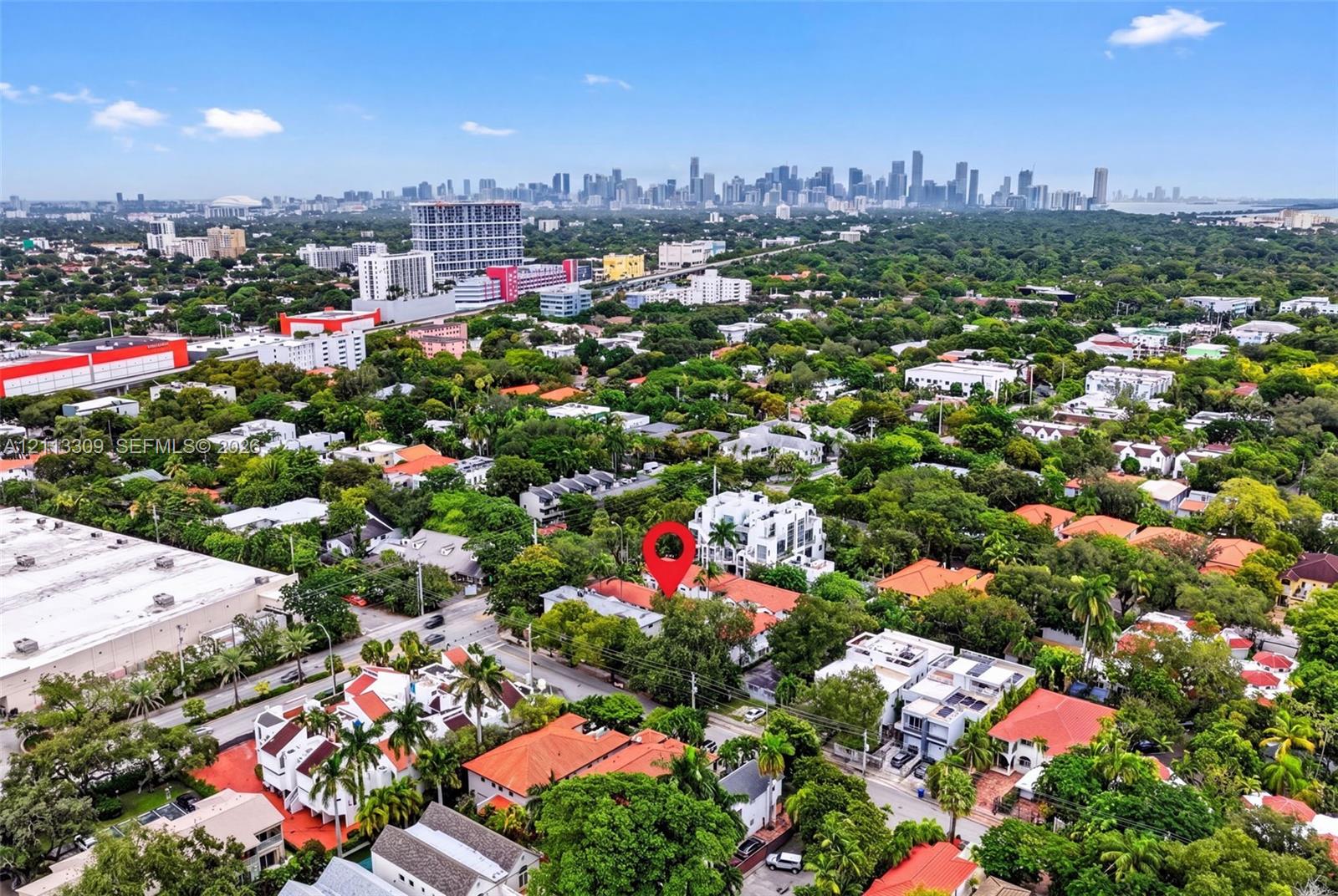 Aerial perspective showcasing a mature, tree-lined neighborhood with expansive urban skyline scenery