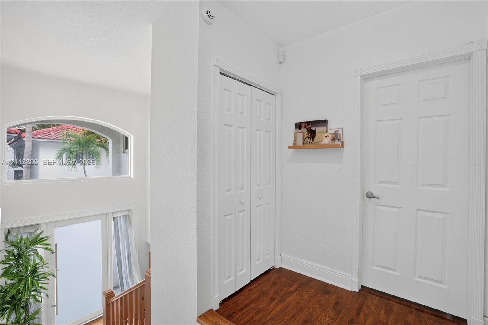 Wood-finish flooring, white paneled interior doors, bi-fold closet doors, and a semi-circular fixed window