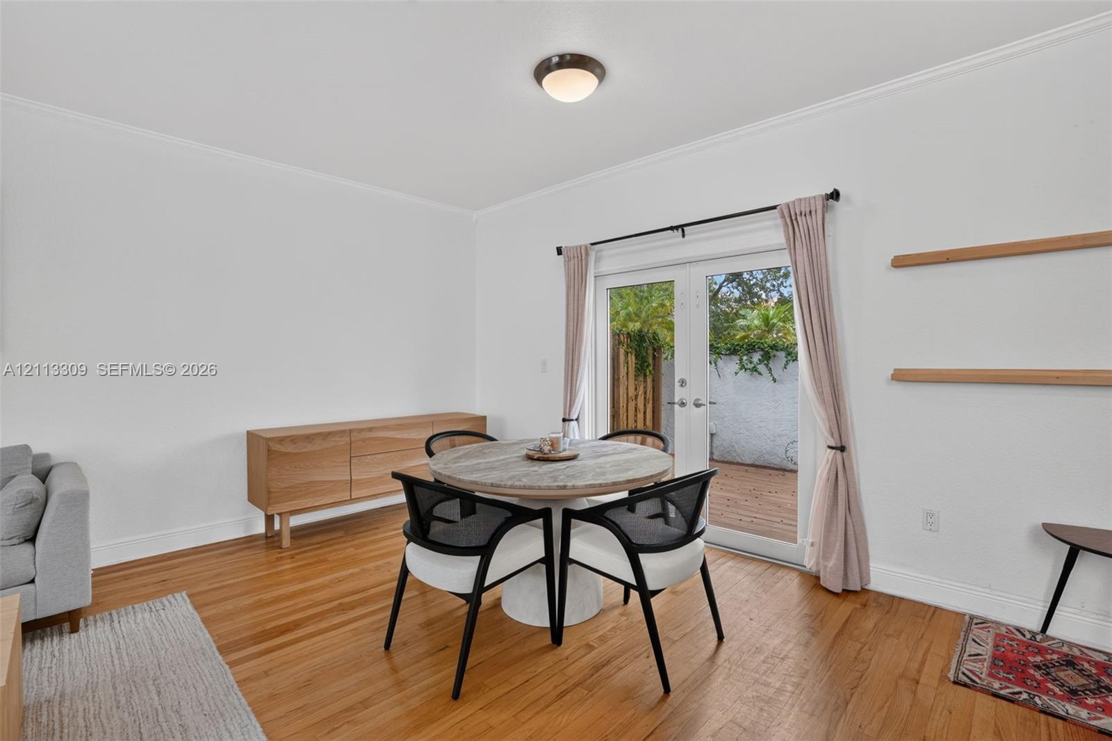 Wood-finish flooring, white walls, dual glass-paneled doors with exterior access, and dual built-in wall-mounted shelves