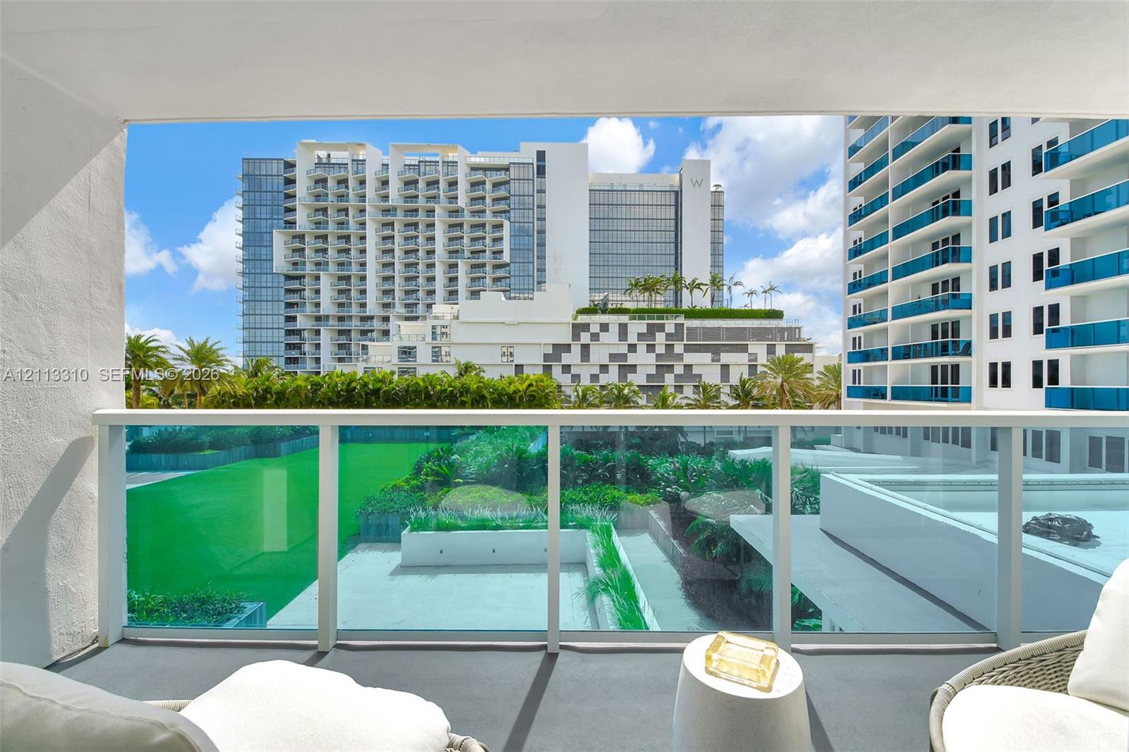 Covered balcony featuring a glass panel railing and solid surface flooring