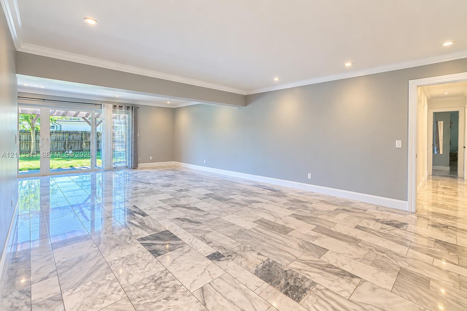 Polished stone flooring, recessed ceiling lighting, crown molding, and glass sliding doors providing exterior access