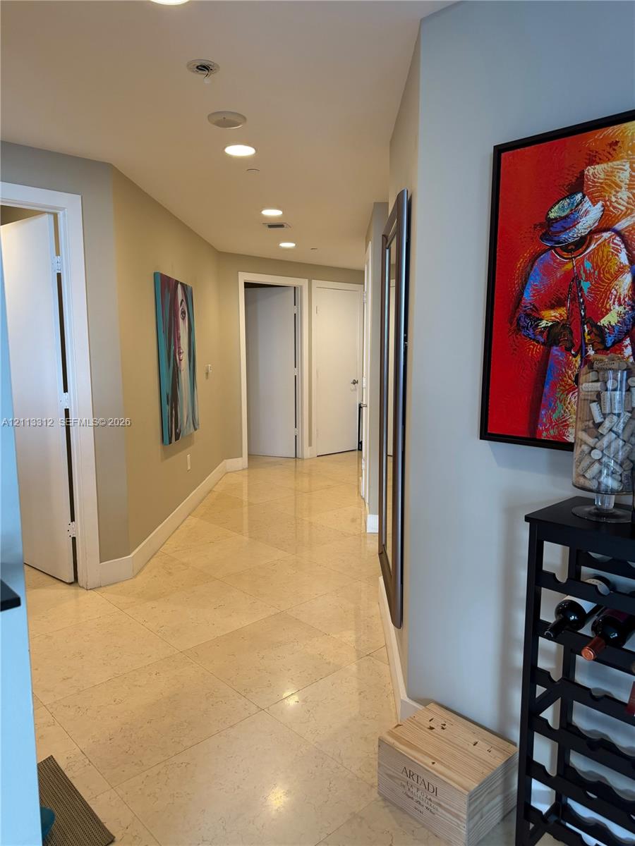 Hallway featuring polished stone tile flooring and recessed ceiling lighting
