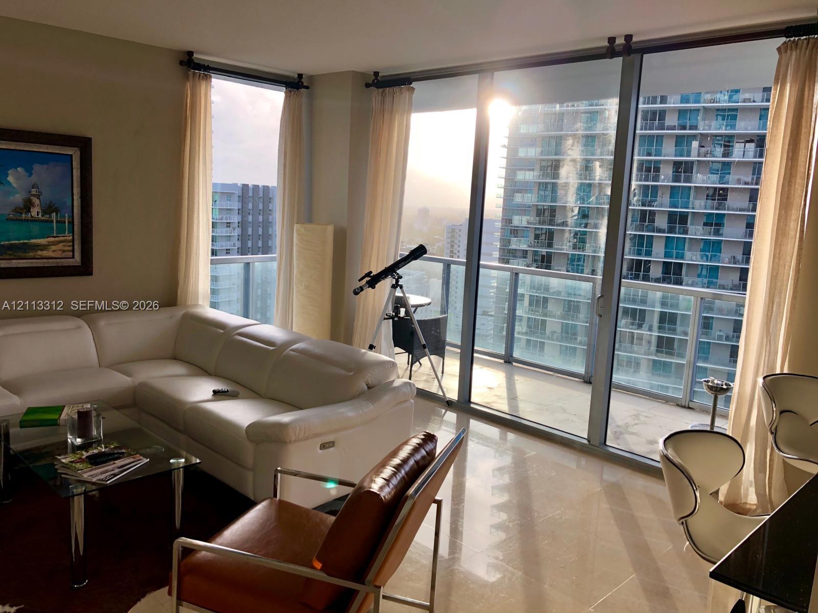 Floor-to-ceiling windows, polished stone flooring, and a glass-paneled balcony