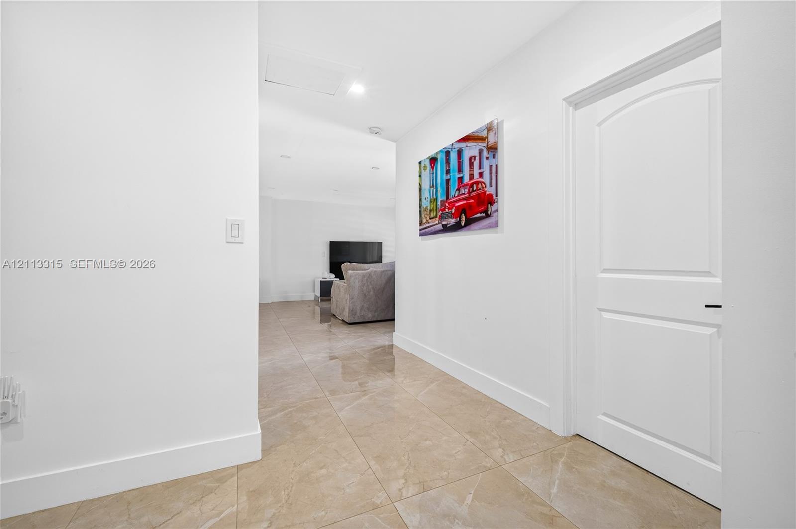 Hallway featuring large-format tile flooring, a solid-core interior door with arched detailing, and recessed lighting