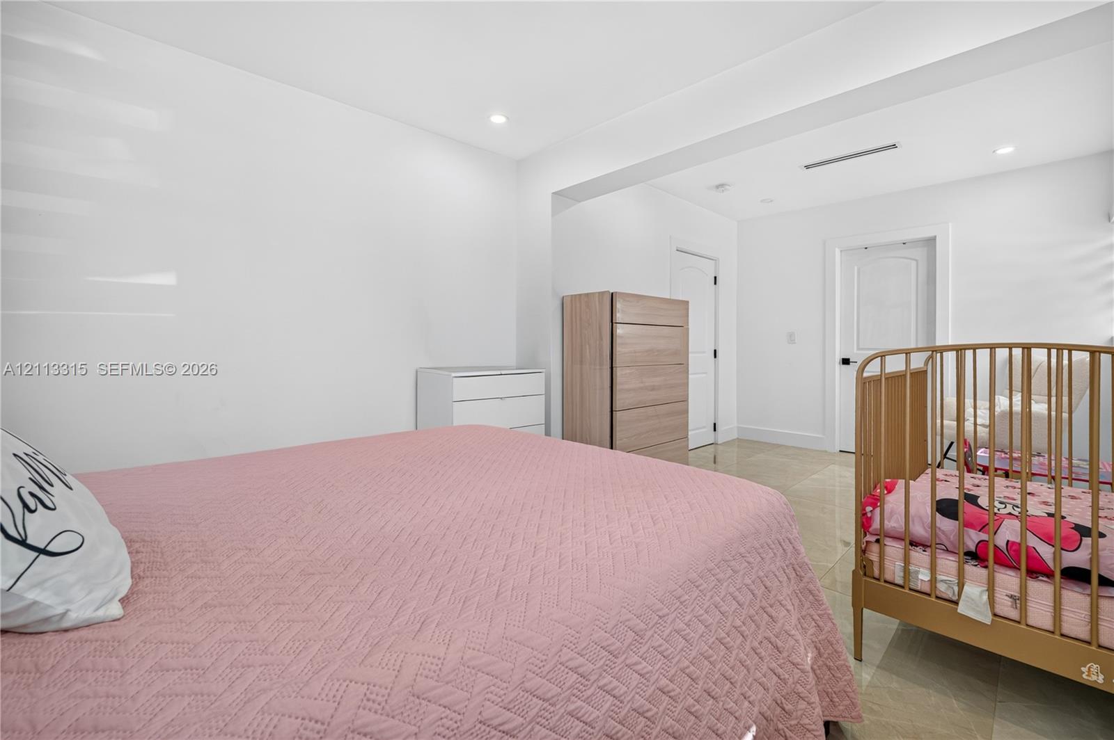 Neutral interior featuring white walls, recessed ceiling lighting, light-toned tile flooring, and solid-core interior doors