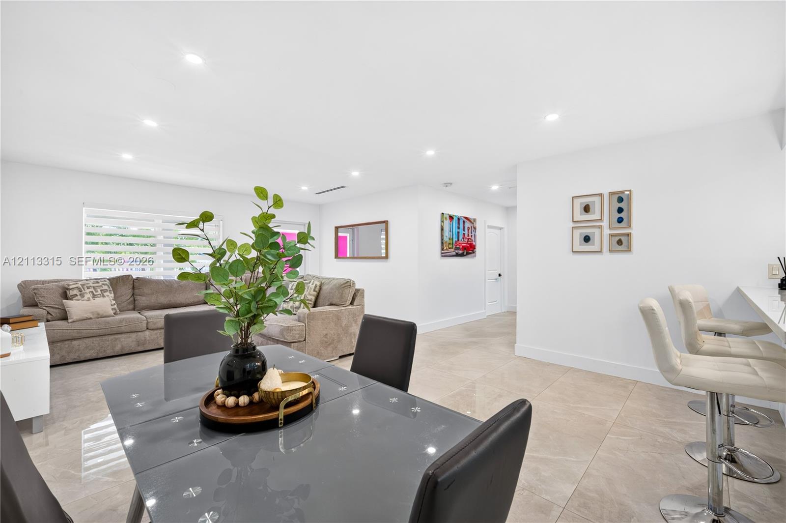Open-concept interior featuring large-format tile flooring, recessed lighting, and a breakfast bar