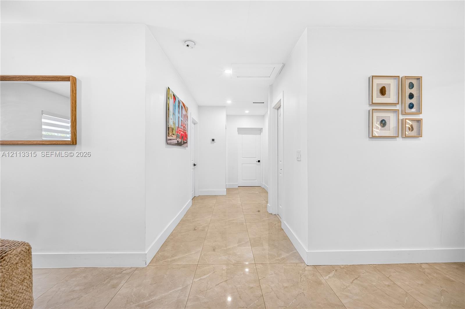 Neutral-toned polished tile flooring, crisp white walls, recessed ceiling lighting, and solid-core interior doors with matte black hardware