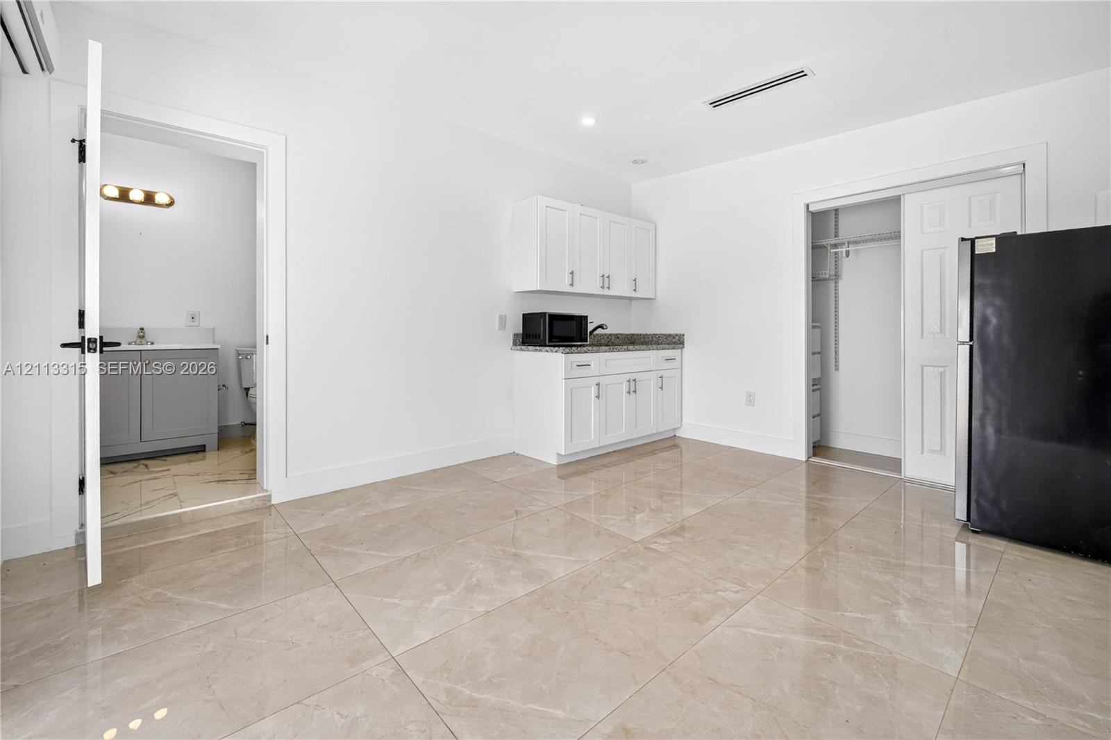 Polished stone-finish flooring, white shaker-style cabinetry with stone-surface countertops, and recessed ceiling lighting