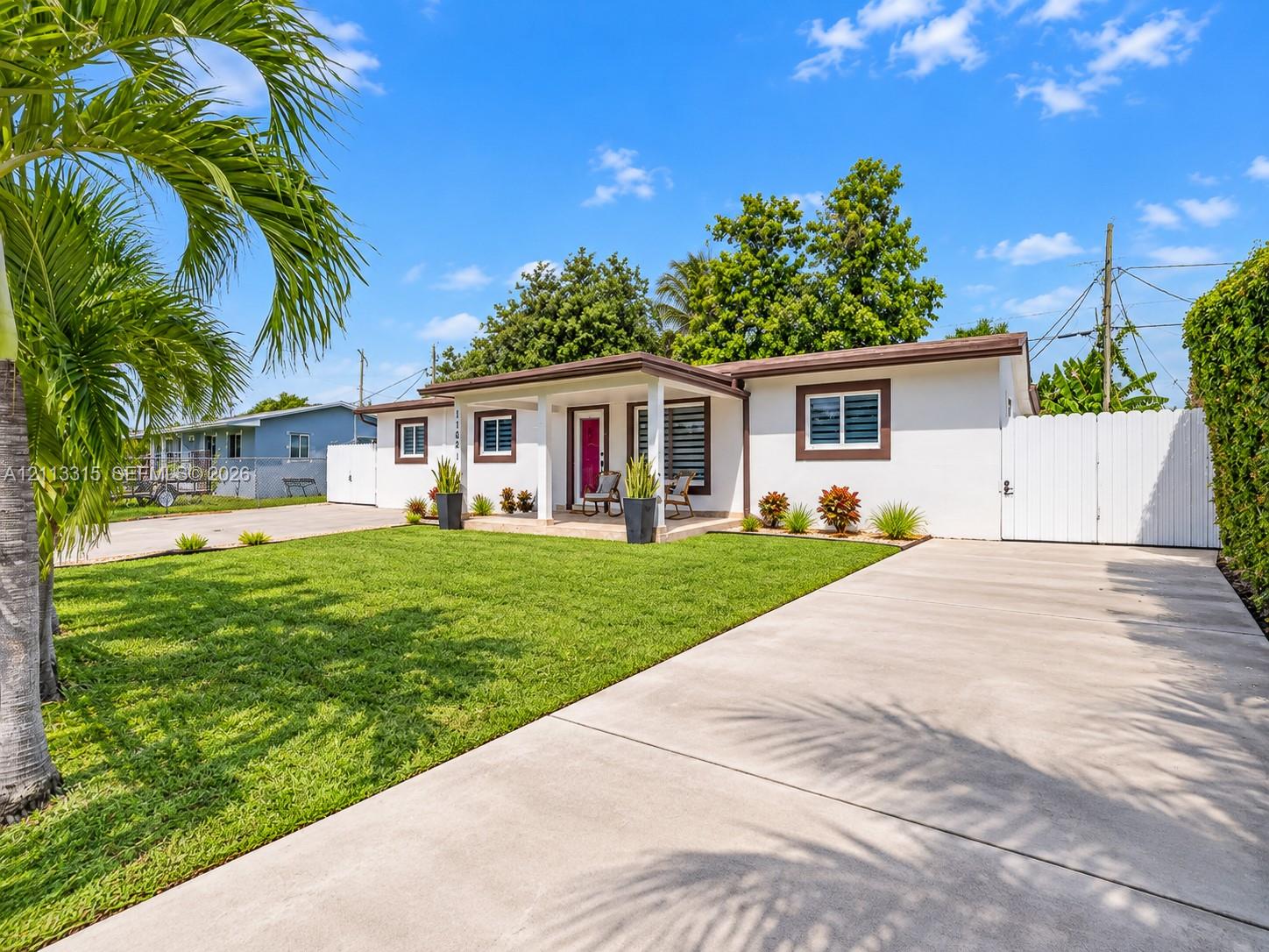 Single-story exterior featuring white stucco siding, a covered front entryway, a concrete driveway, and a white privacy fence
