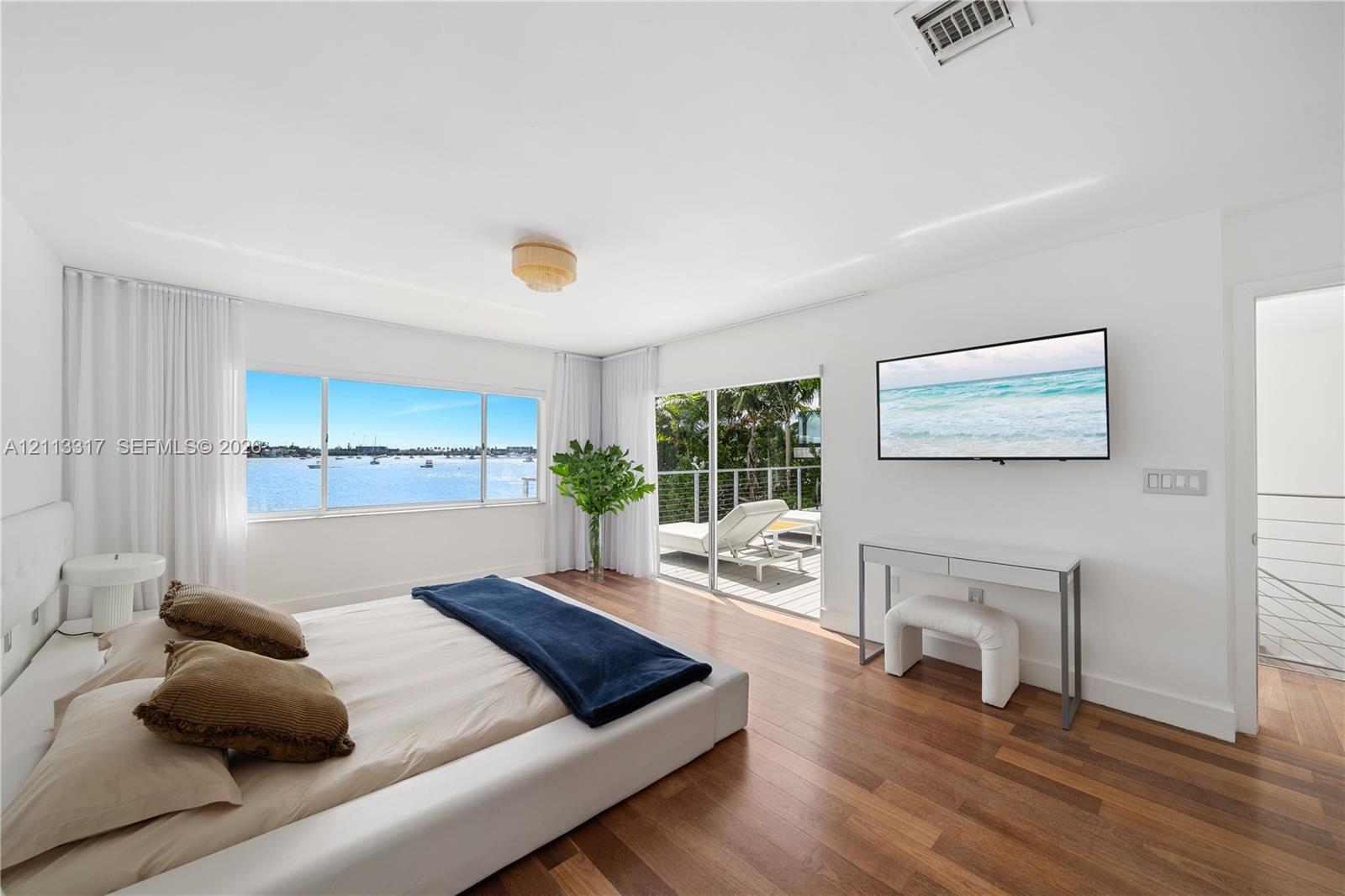 Hardwood flooring, expansive horizontal windows, recessed ceiling lighting, and sliding glass doors opening to a balcony