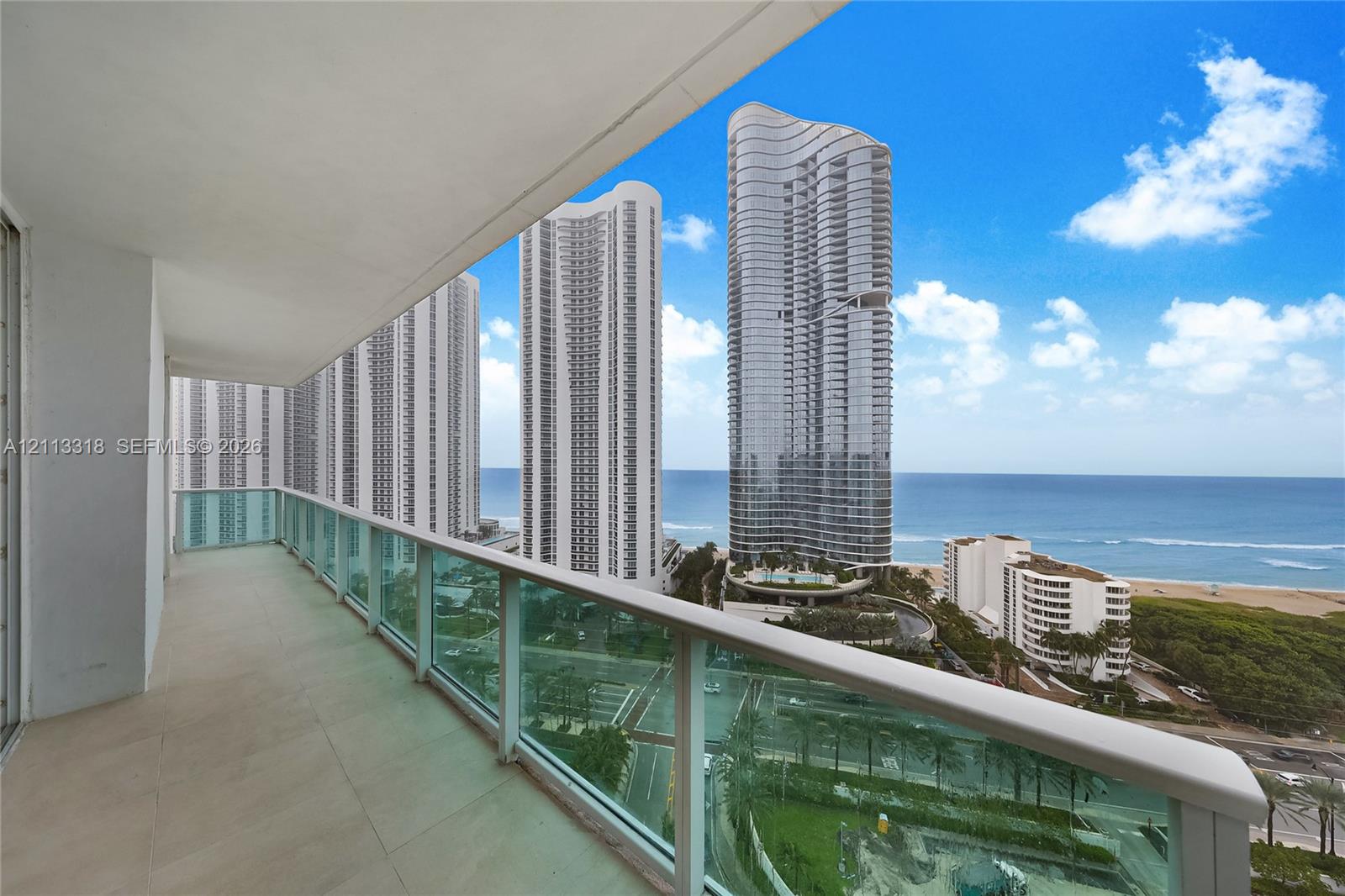 Covered balcony featuring neutral large-format tile flooring and a glass panel railing