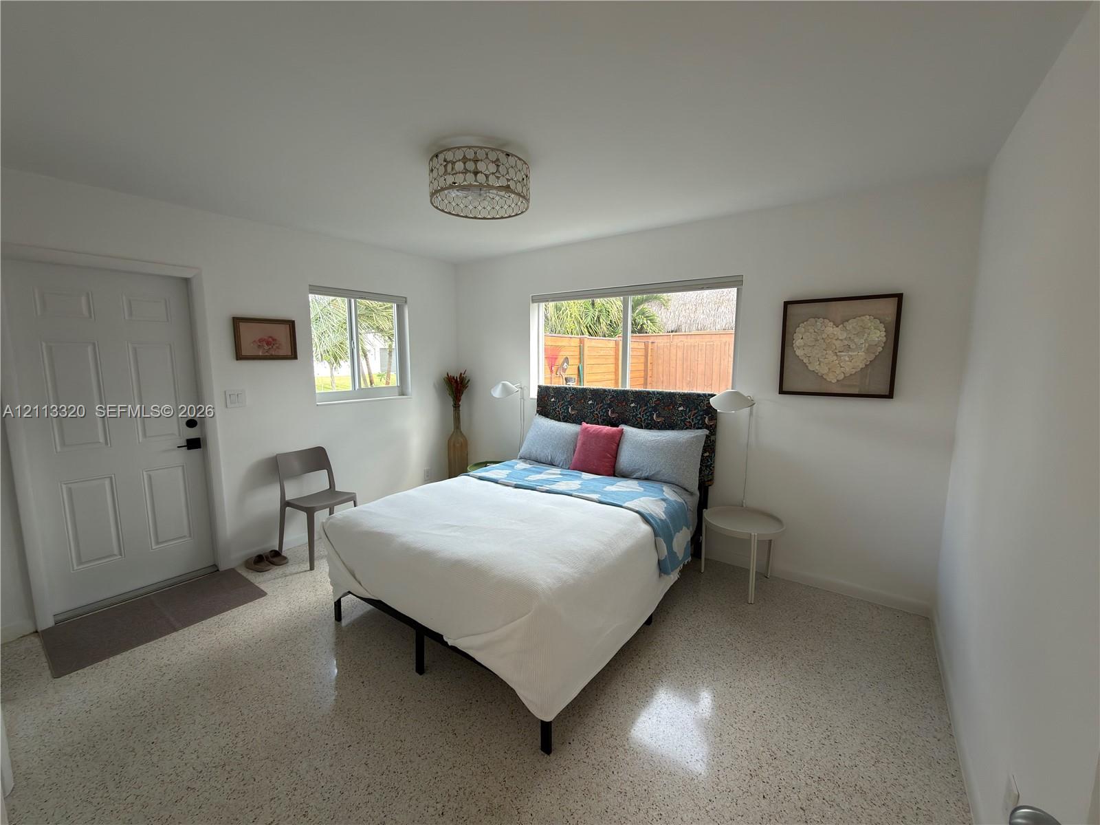 Neutral-toned terrazzo flooring, recessed window frames, and decorative drum-style ceiling lighting