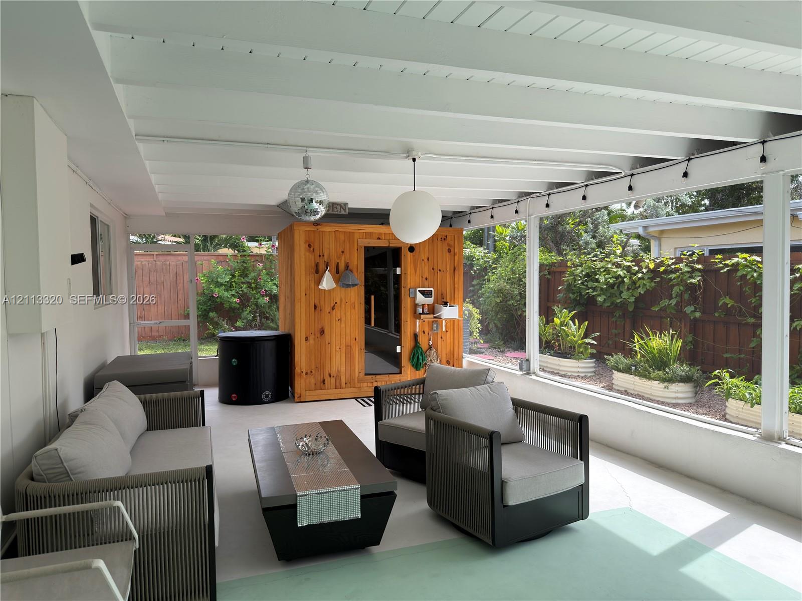 Screened-in patio featuring a vaulted ceiling with exposed beams, wood-paneled sauna, and concrete flooring