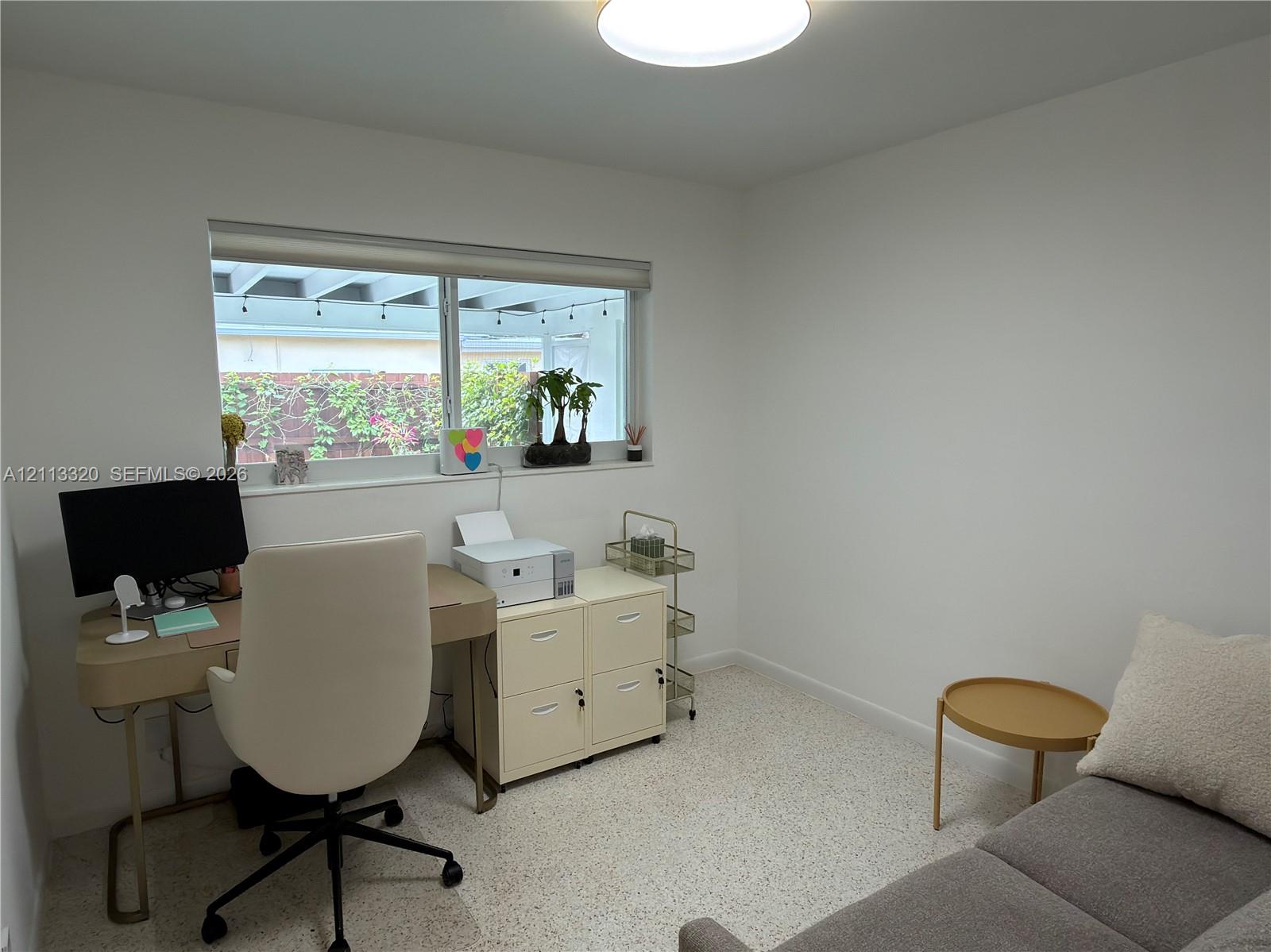 Neutral-toned interior space featuring light-colored stone-flecked flooring, a wide horizontal window, and a recessed ceiling lighting fixture