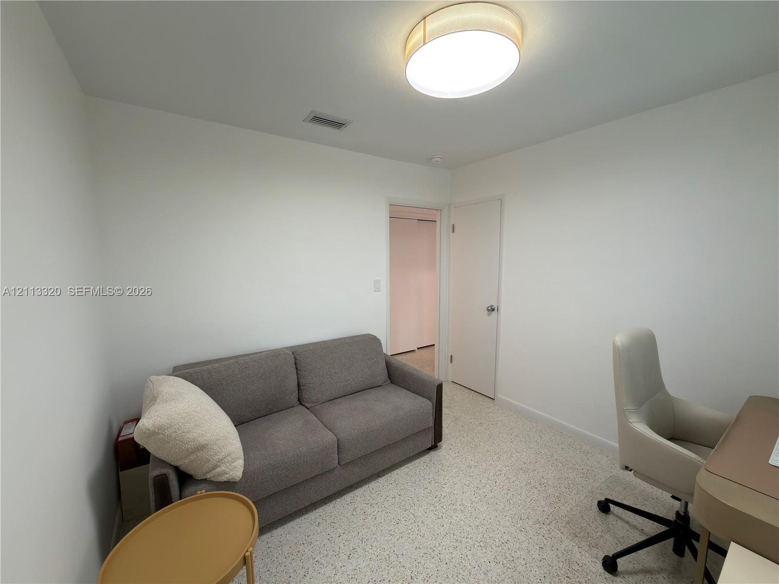 Neutral-toned walls, terrazzo flooring, and a circular flush-mount ceiling light fixture