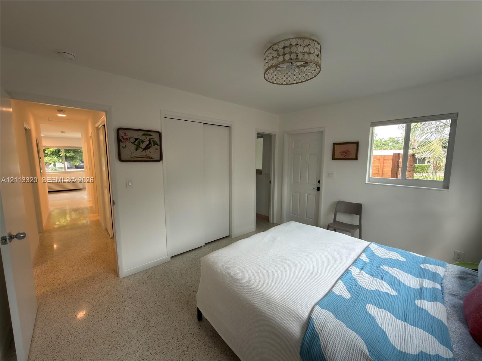 Terrazzo flooring, semi-flush mount drum ceiling light with decorative trim, sliding door closet, and multi-pane horizontal sliding window