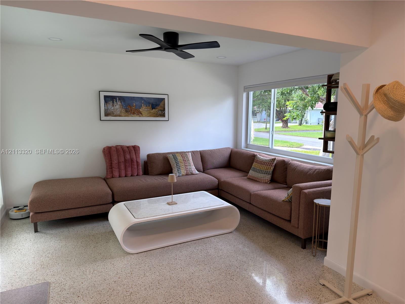 Living area featuring terrazzo flooring, large picture window, recessed lighting, and matte black ceiling fan